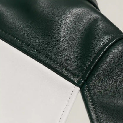 Close-up of a dark green pebbled leather material meeting a white leather panel, showing clean stitching and a curved seam.